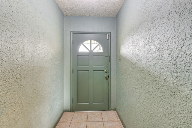 doorway to outside with light tile patterned floors and a textured ceiling