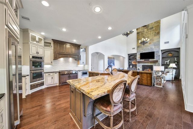 kitchen featuring a large island, a breakfast bar, stainless steel appliances, light stone counters, and cream cabinets