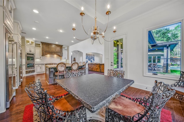 dining area featuring crown molding, dark hardwood / wood-style floors, and an inviting chandelier