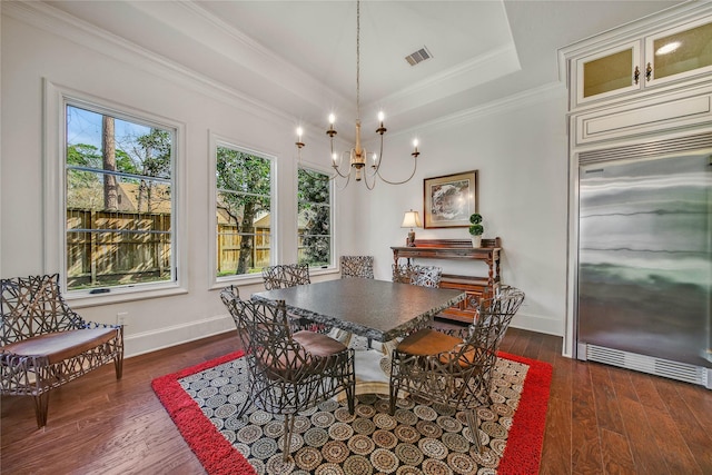 dining area with ornamental molding, dark hardwood / wood-style floors, an inviting chandelier, and a tray ceiling