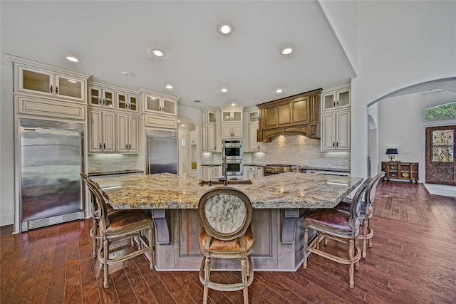 kitchen featuring a large island, cream cabinets, light stone counters, and appliances with stainless steel finishes