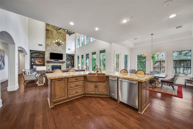 kitchen featuring an island with sink, light stone countertops, sink, and stainless steel dishwasher