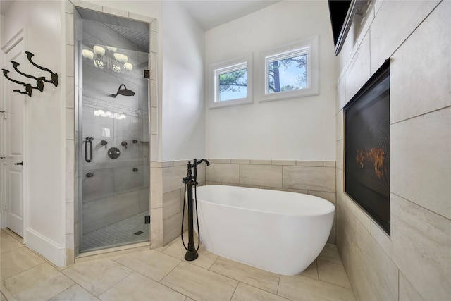 bathroom featuring plus walk in shower, tile patterned flooring, and tile walls