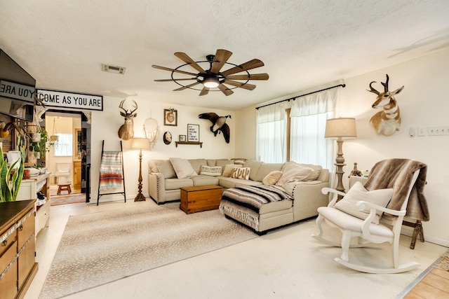 living room featuring ceiling fan and a textured ceiling