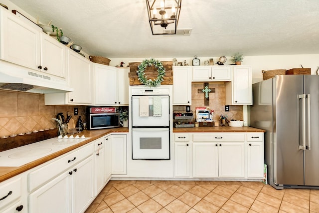 kitchen with light tile patterned flooring, white cabinetry, backsplash, stainless steel appliances, and a textured ceiling