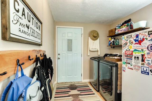 clothes washing area featuring washer and clothes dryer and a textured ceiling