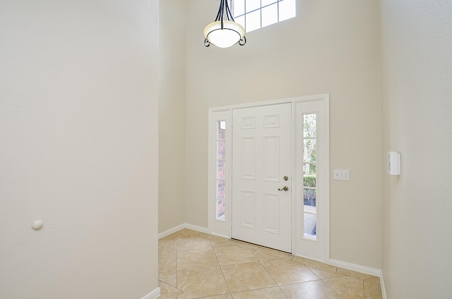 foyer featuring plenty of natural light, a towering ceiling, and light tile patterned floors