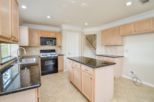 kitchen with range with gas cooktop, sink, dark stone counters, ornamental molding, and a center island