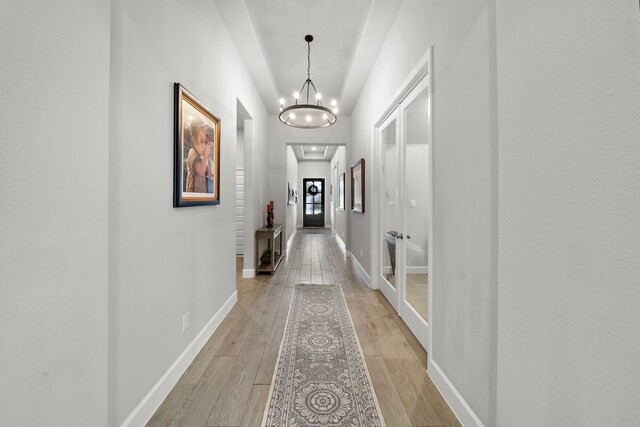 hallway with an inviting chandelier and light wood-type flooring