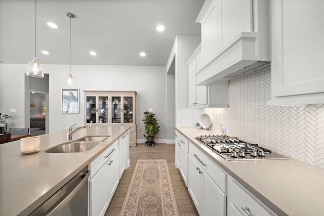 kitchen featuring custom exhaust hood, sink, pendant lighting, and white cabinets