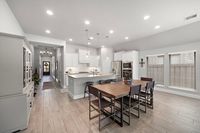 dining area featuring sink, a notable chandelier, and light wood-type flooring