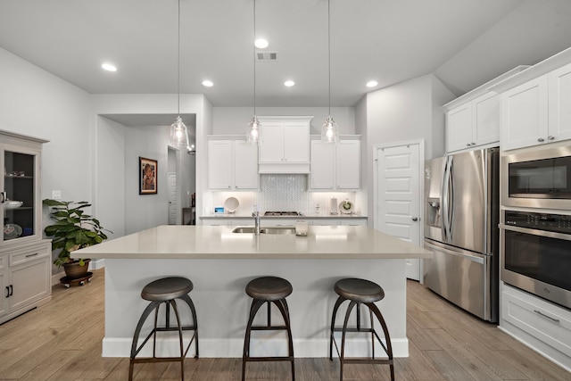 kitchen with a kitchen island with sink, hanging light fixtures, and stainless steel appliances