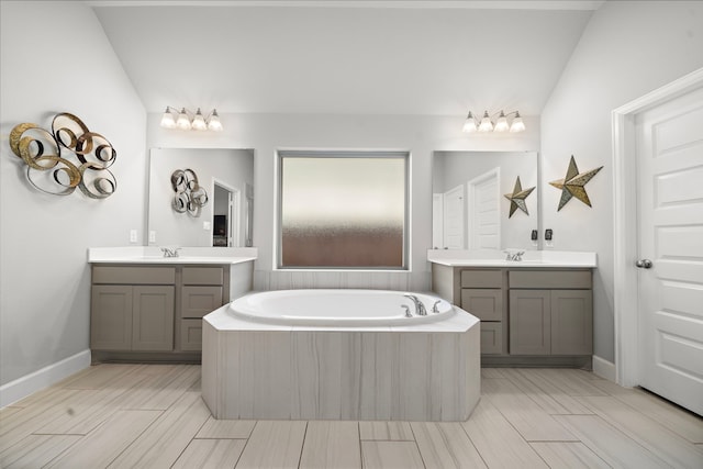 bathroom featuring vanity, vaulted ceiling, and tiled bath