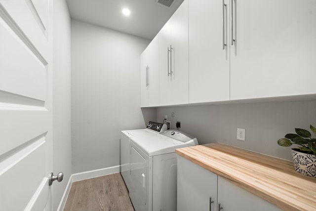 washroom with cabinets, washer and dryer, and light wood-type flooring