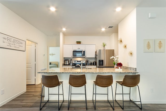 kitchen featuring sink, a breakfast bar area, white cabinets, dark hardwood / wood-style flooring, and stainless steel appliances