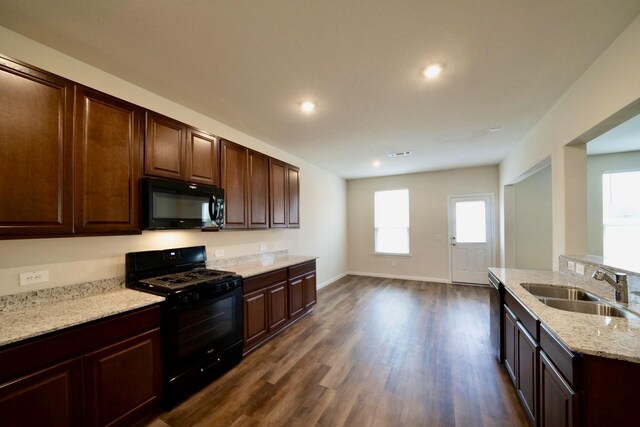 kitchen featuring sink, dark brown cabinets, dark hardwood / wood-style flooring, light stone countertops, and black appliances