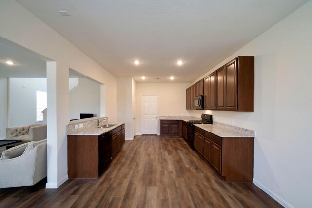 kitchen with dark hardwood / wood-style floors, black appliances, sink, light stone counters, and dark brown cabinetry