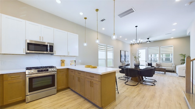 kitchen featuring pendant lighting, kitchen peninsula, white cabinets, and appliances with stainless steel finishes