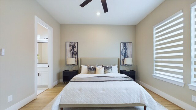 bedroom with multiple windows, ensuite bath, light hardwood / wood-style flooring, and ceiling fan