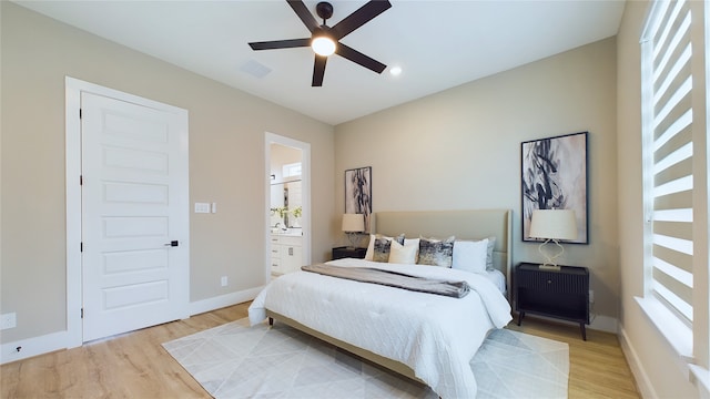 bedroom featuring ceiling fan, ensuite bath, and light hardwood / wood-style flooring