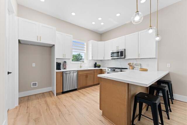 4013 Griggs Rd Unit L, Houston, TX 77021 - kitchen with a kitchen breakfast bar, stainless steel appliances, a peninsula, and light wood-style flooring