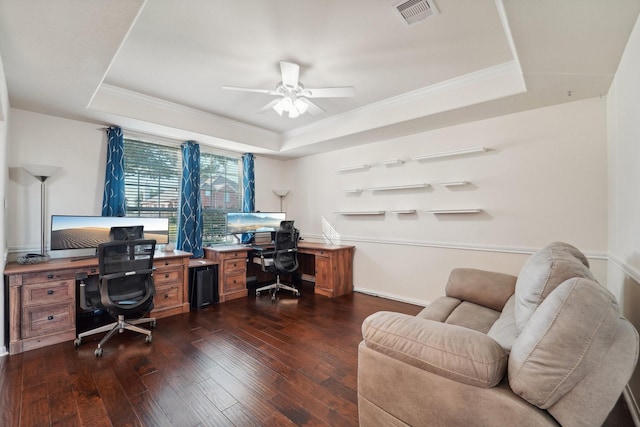 home office featuring dark wood-type flooring, ceiling fan, ornamental molding, and a raised ceiling