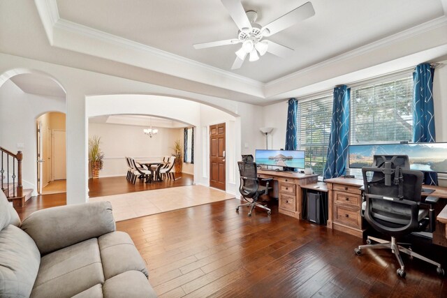 office area featuring ceiling fan with notable chandelier, dark wood-type flooring, ornamental molding, and a raised ceiling