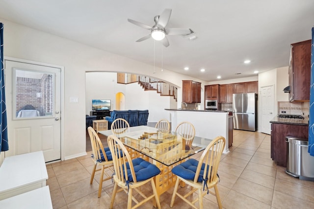 tiled dining room with ceiling fan and sink