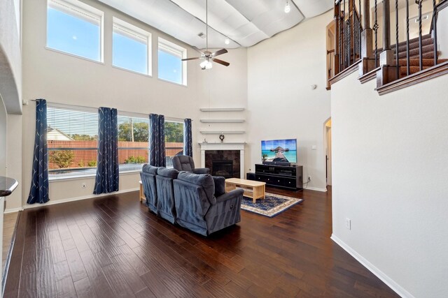 living room with dark wood-type flooring, ceiling fan, and a towering ceiling