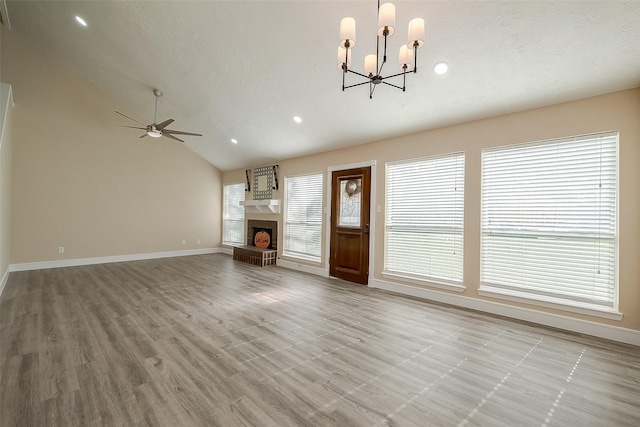 unfurnished living room with vaulted ceiling, ceiling fan with notable chandelier, a textured ceiling, and light hardwood / wood-style floors