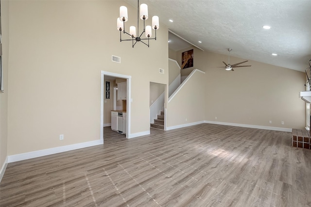 unfurnished living room with high vaulted ceiling, ceiling fan with notable chandelier, a textured ceiling, and light hardwood / wood-style floors