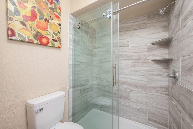 bathroom featuring toilet and a shower with door