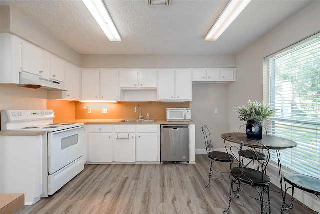 kitchen with sink, light wood-type flooring, white cabinets, white appliances, and a textured ceiling