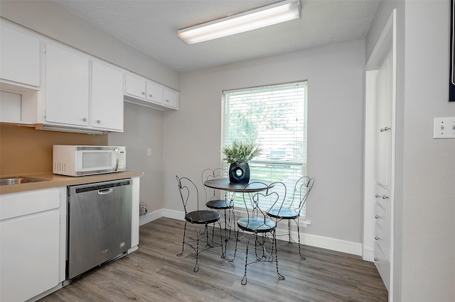 kitchen with white cabinetry, dishwasher, and light hardwood / wood-style floors