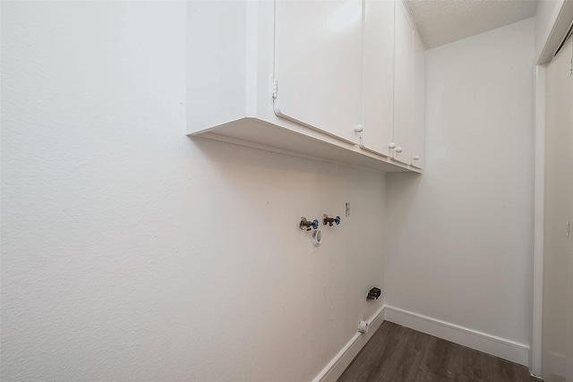 clothes washing area featuring dark wood-type flooring, cabinets, and a textured ceiling