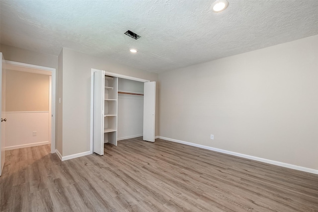 unfurnished bedroom with light hardwood / wood-style flooring, a closet, and a textured ceiling