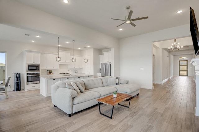 living room featuring recessed lighting, light wood-style flooring, a healthy amount of sunlight, baseboards, and ceiling fan with notable chandelier