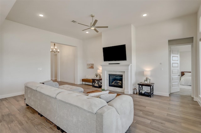 living room with ceiling fan with notable chandelier and light wood-type flooring