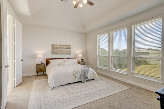 bedroom with light carpet, baseboards, a ceiling fan, lofted ceiling, and a tray ceiling