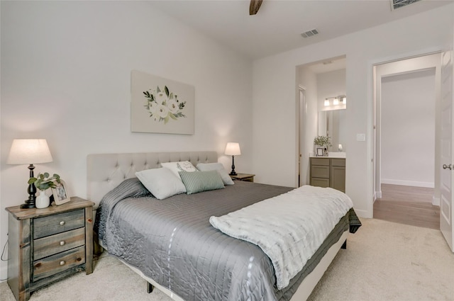 bedroom with light colored carpet and ensuite bath