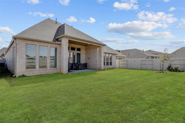 rear view of house featuring a patio, a shingled roof, a lawn, and a fenced backyard