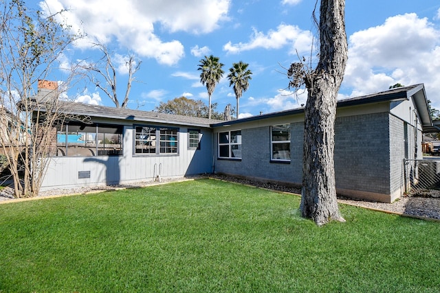 rear view of house featuring a lawn and central air condition unit