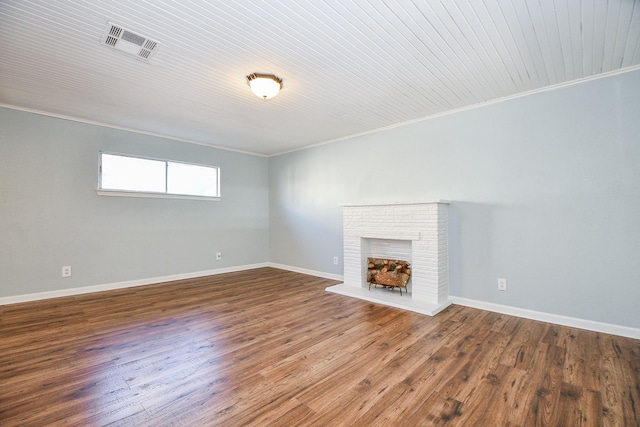 unfurnished living room with wood ceiling, ornamental molding, a brick fireplace, and wood-type flooring