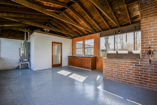 misc room with vaulted ceiling, water heater, and brick wall