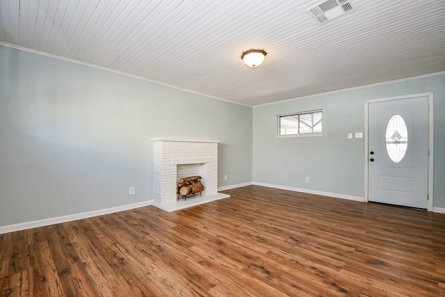 unfurnished living room featuring ornamental molding, a brick fireplace, and dark hardwood / wood-style floors