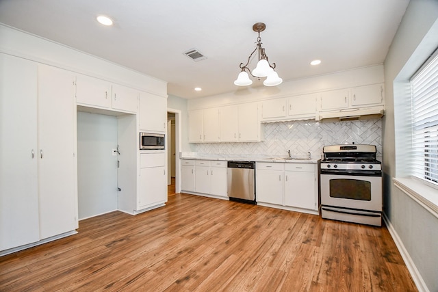 kitchen featuring white cabinetry, hanging light fixtures, and appliances with stainless steel finishes