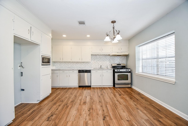 kitchen with hanging light fixtures, white cabinets, and appliances with stainless steel finishes