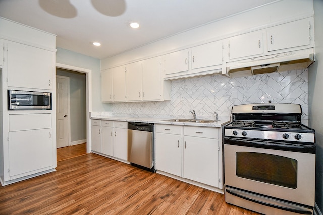 kitchen with sink, appliances with stainless steel finishes, backsplash, white cabinets, and light wood-type flooring