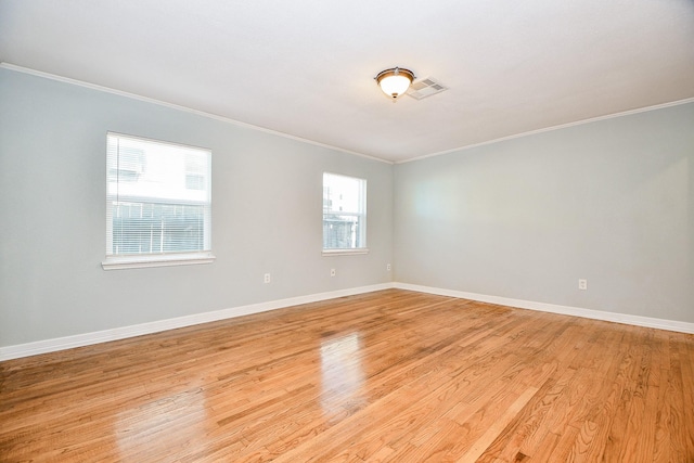 empty room with crown molding and light hardwood / wood-style floors