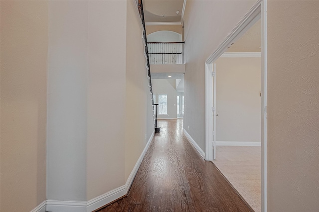 hall with a towering ceiling, wood-type flooring, and ornamental molding